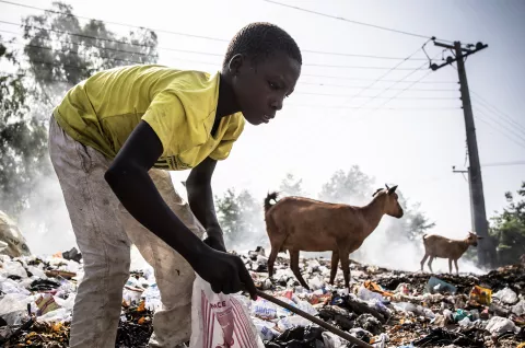 An adolescent boy digs through a rubbish dump for saleable items, Nigeria